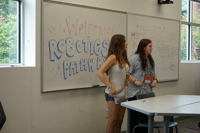 Student standing in front of a sign that says "Welcome Robotics Pathway"