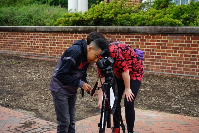 Student and woman looking through a camera