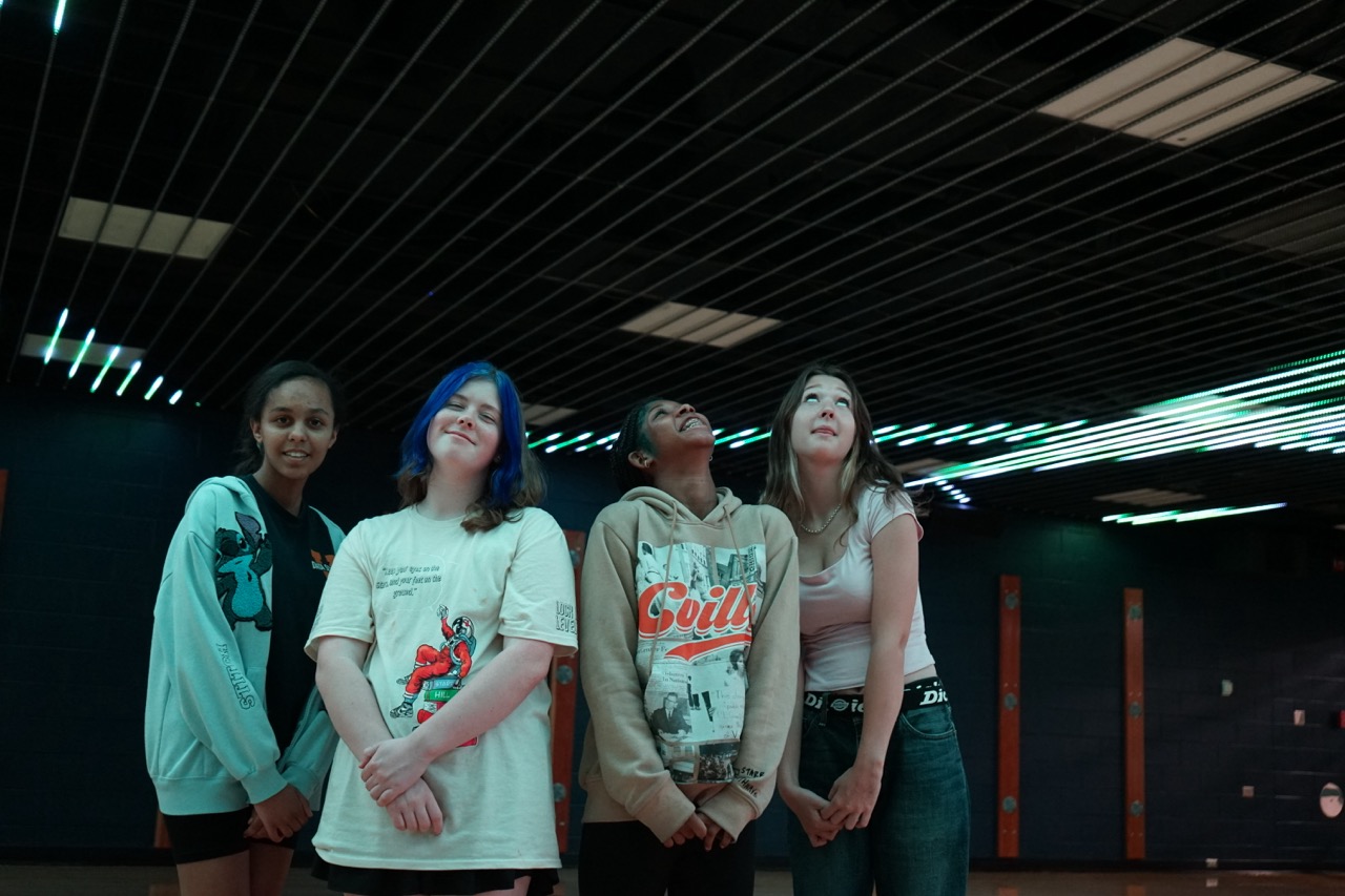 Students pose under colorful lights