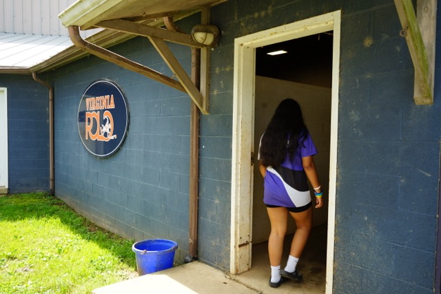 Student walking into a stable at Virginia Polo