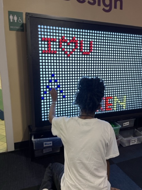 Student writing "I love you" on a screen