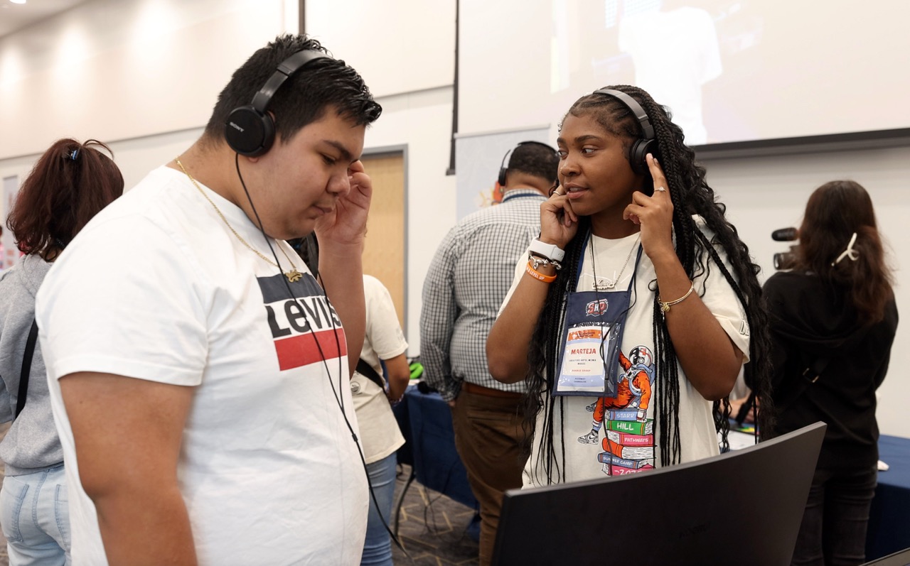 Student and counselor listening to headphones connected to a computer