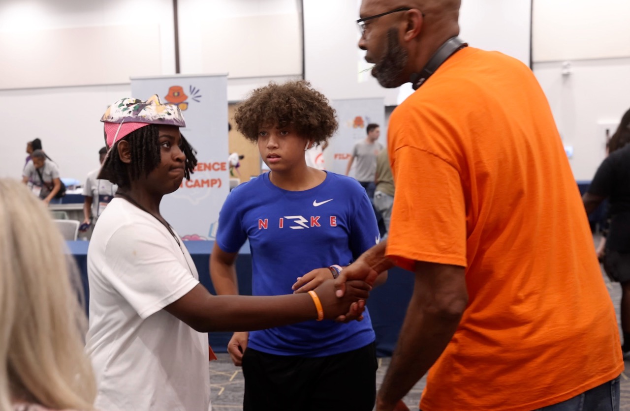 Students shaking hands with an expo attendee