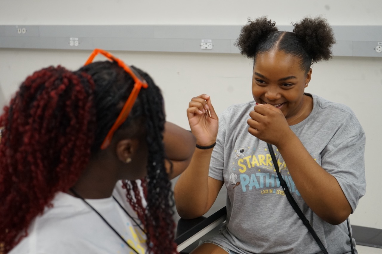 A student laughs while talking to a camp counselor.